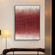 The Gridelle Crimson Fade Gradient Grid 3D Paper Wall Art by Giant Sculptures, featuring small red squares fading to white, hangs above a dark wooden bench on a light wall. A floor lamp with a round yellow shade adds inviting warmth nearby.