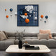 A modern living room with a gray sectional, peach pillows, marble coffee table, and the Aeroluxe Midnight Blue Abstract 3D Wall Art With Metal Balls by Giant Sculptures—featuring blue, orange, and white spheres above the sofa.