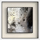 The Stratonis Fragmented Abstract Textured Framed Wall Art by Giant Sculptures features blended black, gray, and white shades with geometric shapes and textured brush strokes, elegantly mounted on a light wall.