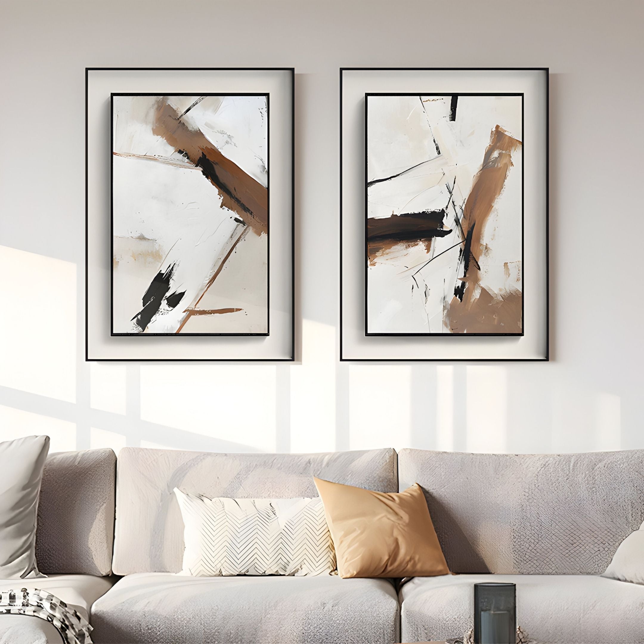 A modern living room features a light gray sofa, beige and cream cushions, and the Bravura IV Stroke Abstract Framed Canvas Wall Art by Giant Sculptures in black, brown, and white above the sofa. Sunlight streams in from the left.