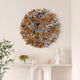The Rivora Amber Ribbon Leather Circular 3D Wall Art by Giant Sculptures, with layered gold, white, and gray abstract shapes, hangs above a white mantel displaying a bust, candles, and a small yellow floral arrangement.