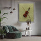 A modern living room features a green velvet armchair, potted plants, a white round side table with dried grass, and the Archetto Olive Violin Acrylic Framed 3D Wall Art by Giant Sculptures displayed on a yellow background.