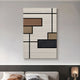 The Gridoria Mocha & Charcoal Linear Block Woven Wall Art by Giant Sculptures, featuring geometric rectangles in brown, tan, black, and navy on a textured cream background, hangs above a modern sofa in a neutral-toned living room.