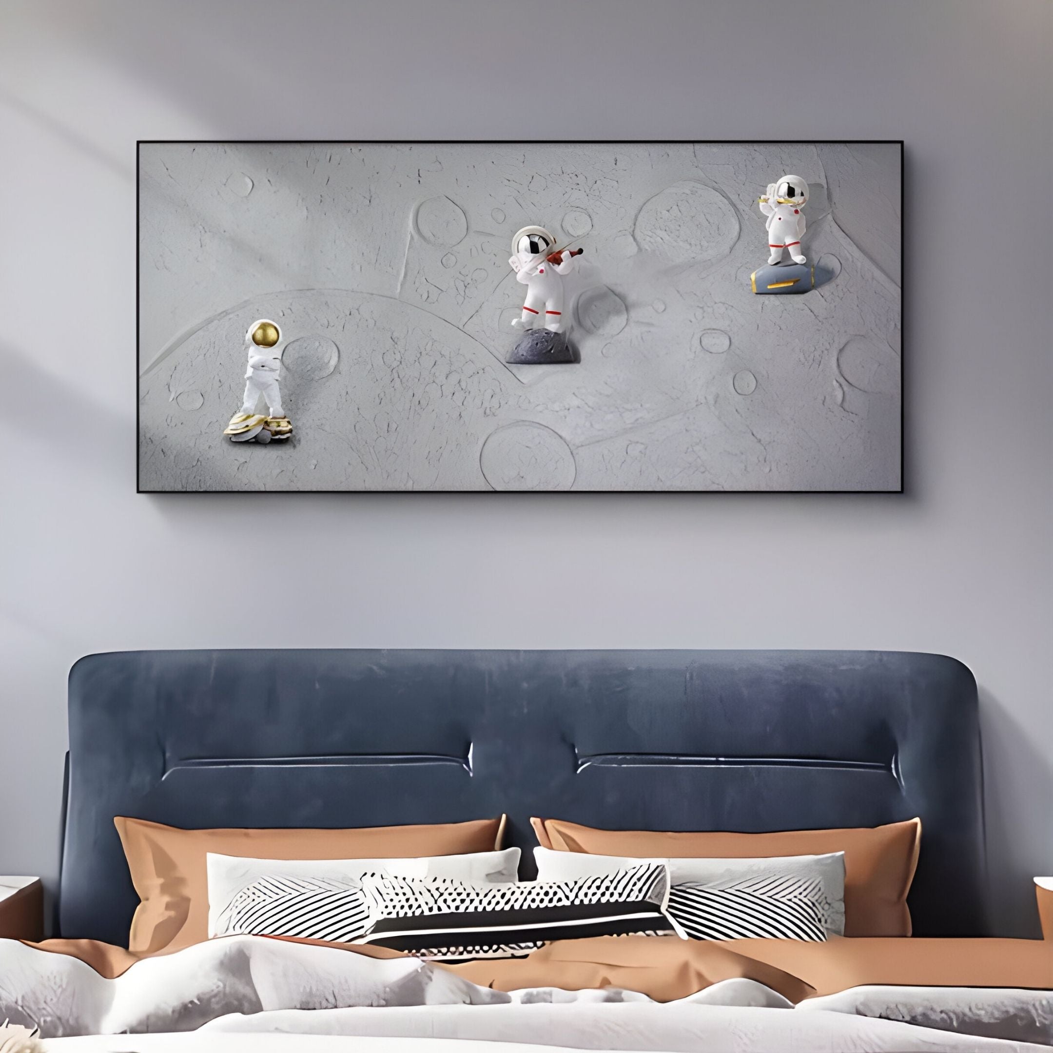 A bedroom with a dark upholstered headboard and brown pillows features Giant Sculptures' Astravera Cosmic Trio Grey Textured Astronaut 3D Wall Art above the bed, adding playful kids room decor charm.