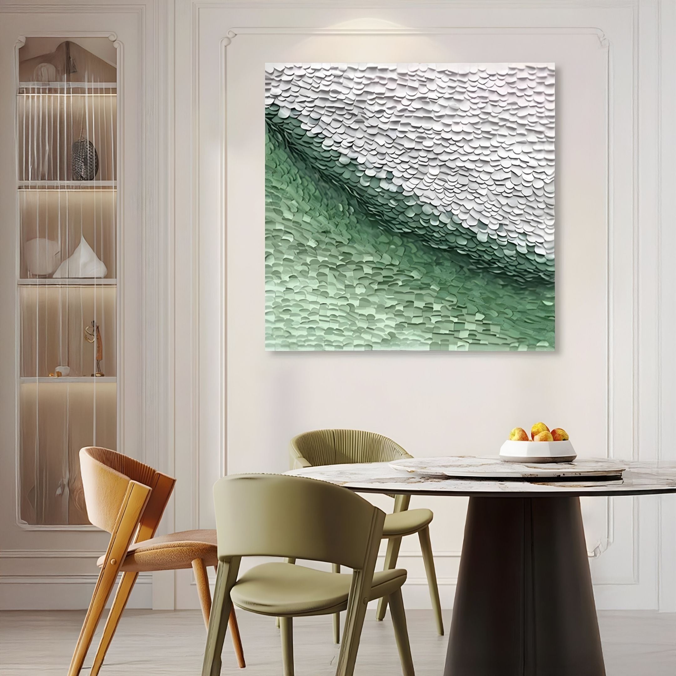 A modern dining area features a round black table, four neutral chairs, a fruit bowl, and the Seravelle Green Gradient Layered 3D Paper Wall Art by Giant Sculptures as a centerpiece. Decor accents on left shelves add extra charm to the stylish space.