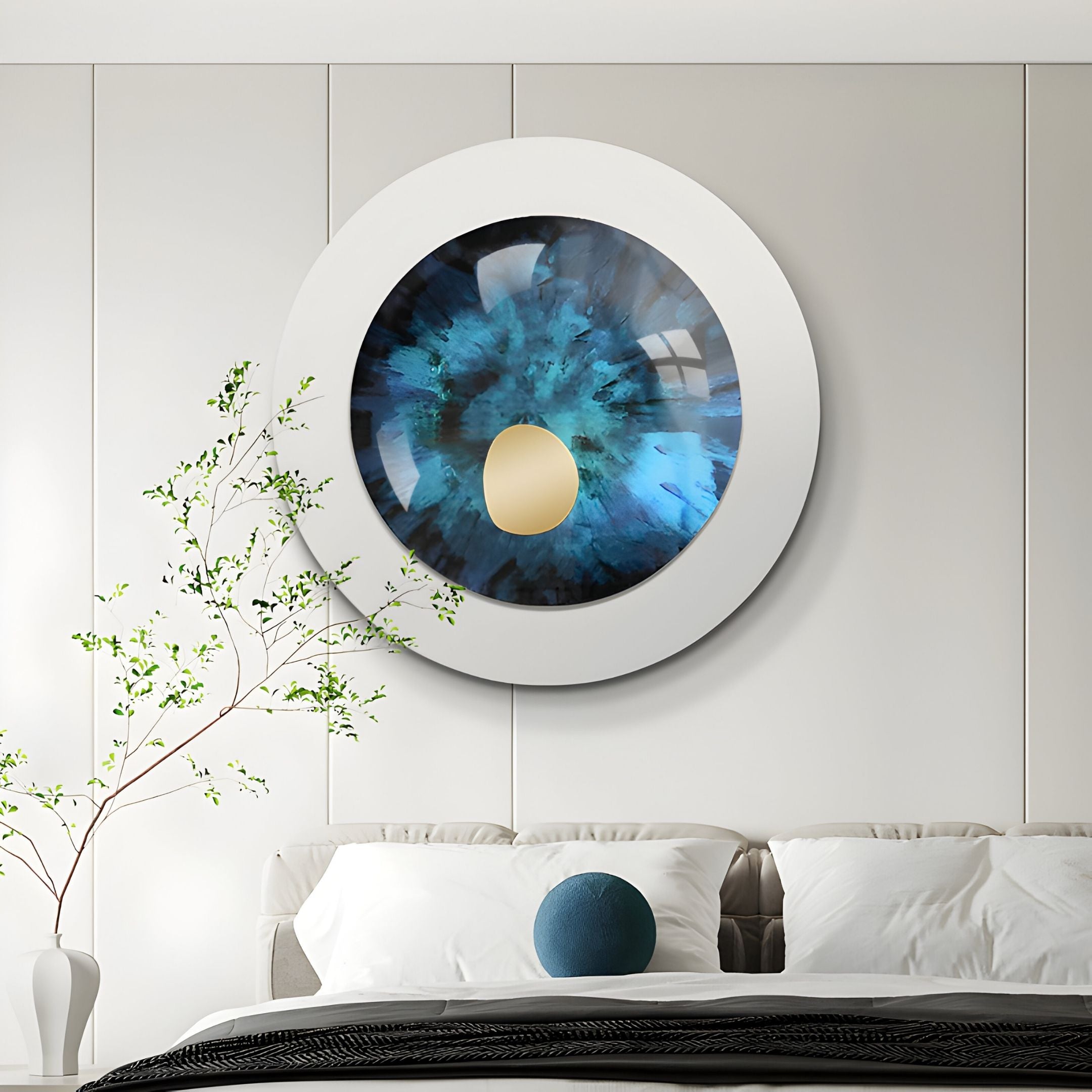 A modern bedroom featuring a white bed with pillows, a green plant, and the Giant Sculptures Iriselle Deep Teal Crystal Porcelain Round 3D Wall Art above the bed on a white paneled wall.
