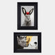 The Ardensir Rabbit & Rhino Surreal 2-Set Framed Wall Art by Giant Sculptures features a rabbit with black ears and a red apple, and a rhinoceros facing a child with gold accents. Both have white backgrounds with faint text.