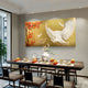 A modern dining room features a long table for six, centered by a vase of white flowers and highlighted by Giant Sculptures' Aurellion White Birds & Red Blossom Gold Panel 3D Button Wall Art. The elegant gold panels create a striking focal point.