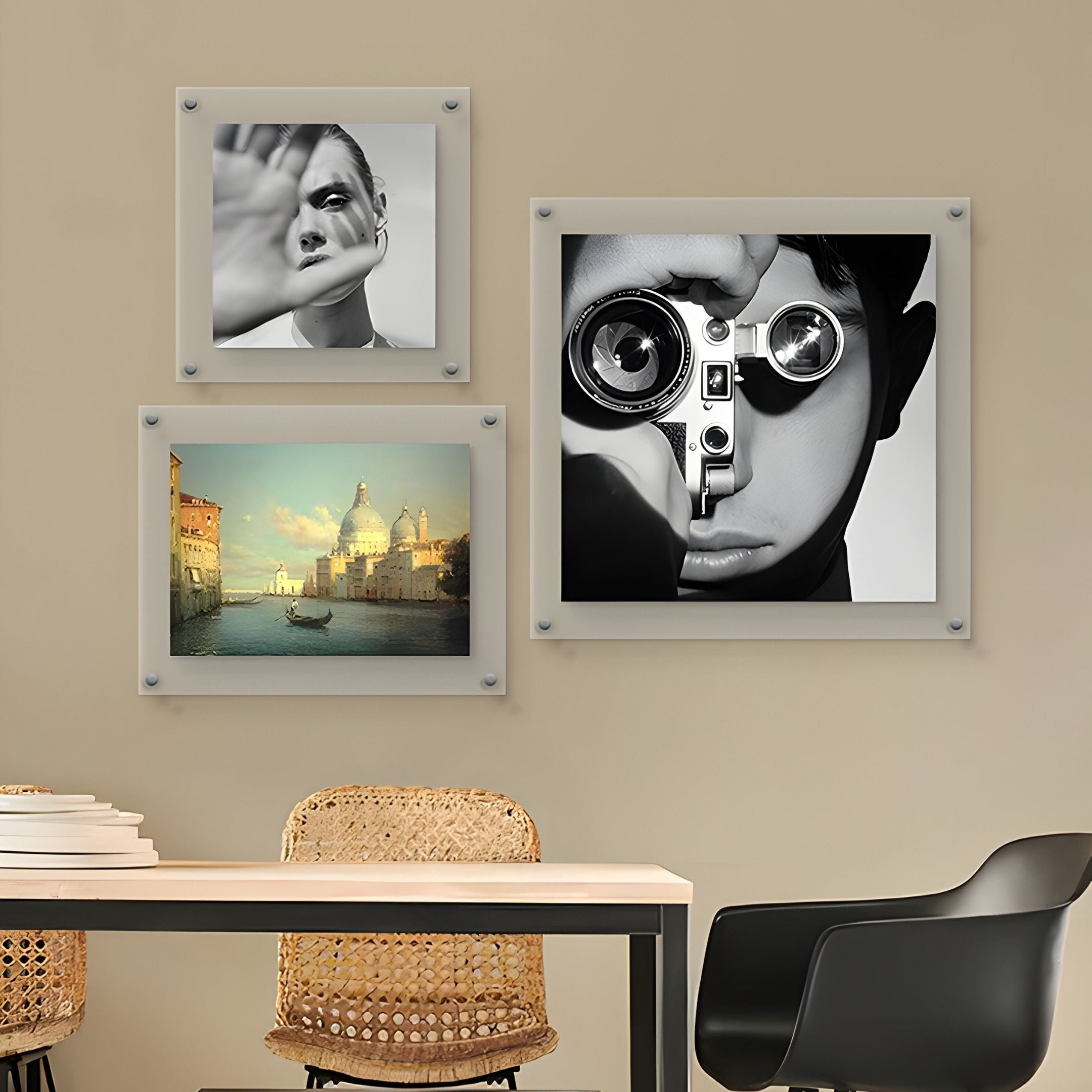 A modern room with a table and black chair showcases Giant Sculptures' CineLuxe Vintage Camera Boy Black & White Portrait Wall Art, alongside vibrant Venice gondola and striking hand-themed acrylic pieces.