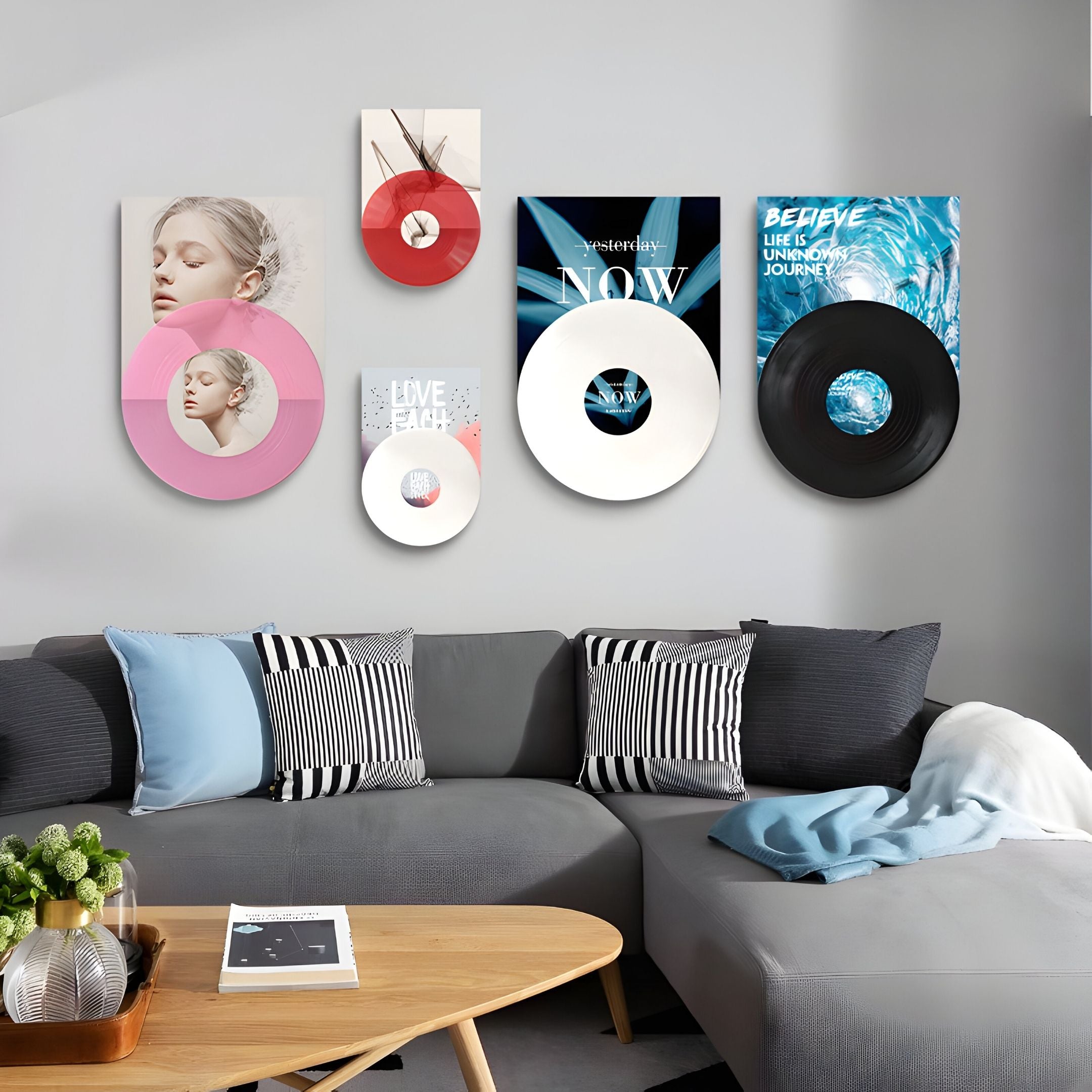 A modern living room with a gray sectional sofa and black-and-white striped pillows. Above, the Groovepost Bold Graphics Vinyl Record 5-Panel Wall Art by Giant Sculptures adds a vibrant focal point with its colorful album-inspired design.