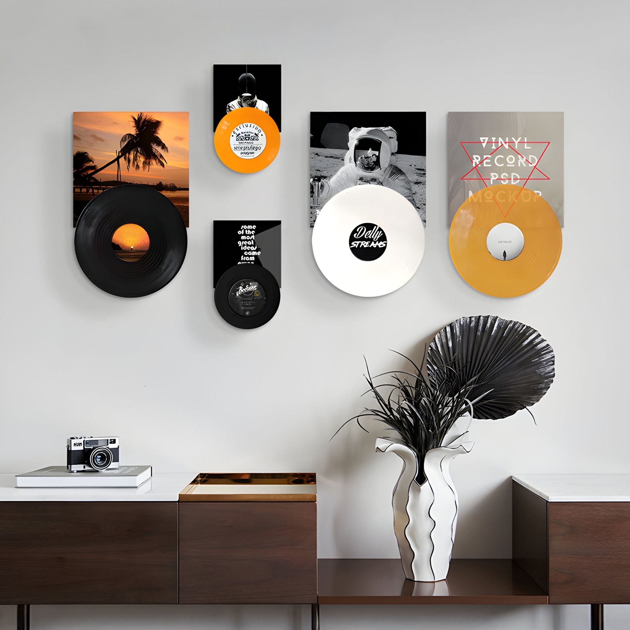 A modern interior features Giant Sculptures' Vinylora Sunset & Space Vinyl Records 5-Panel Wall Art above a wooden console table, styled with a vase of black and silver leaves and a vintage camera for chic music-themed decor.