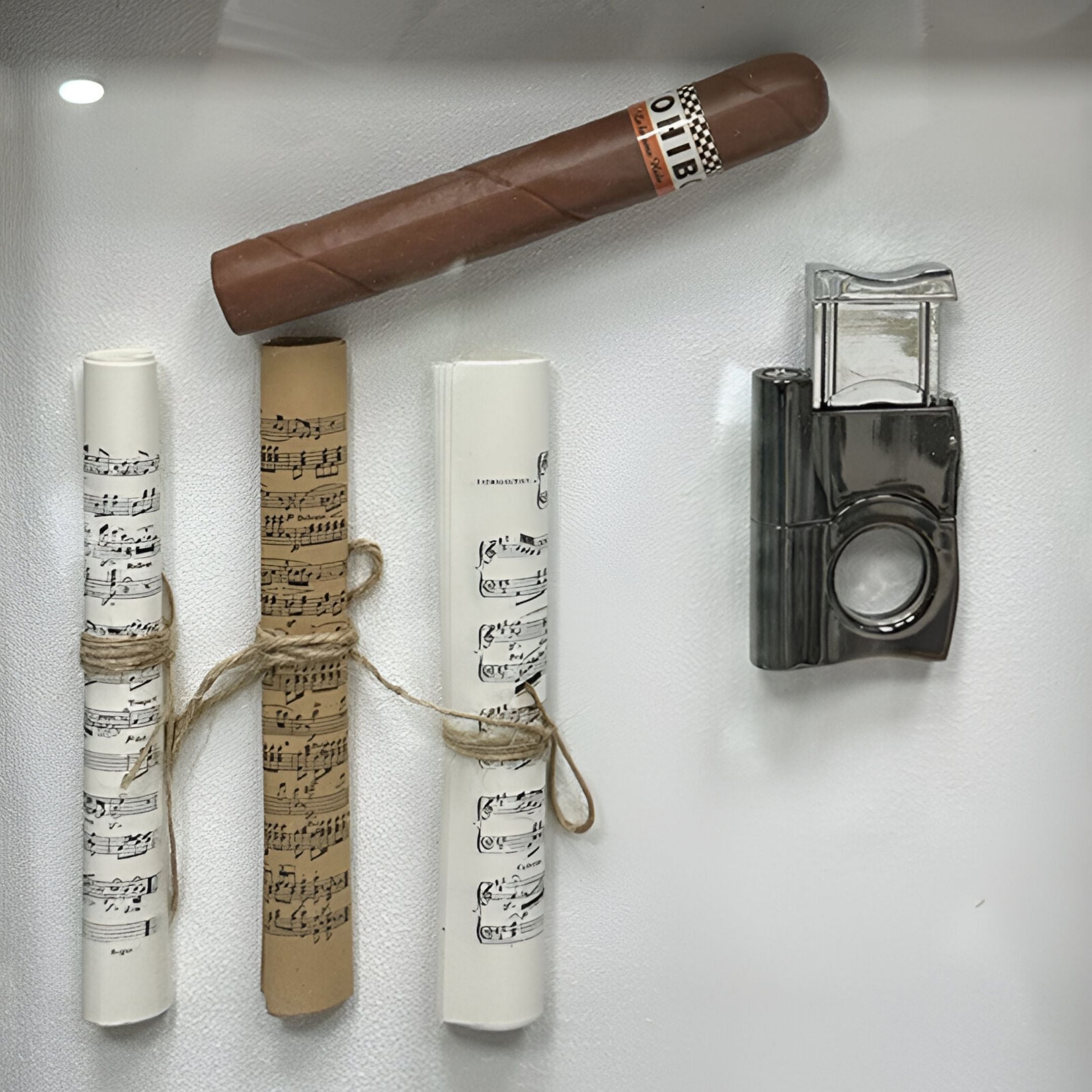 The CurioVault Cigar & Sheet Music Framed Wall Art by Giant Sculptures displays a lifelike cigar, rolled music sheets tied with twine, and a silver lighter—ideal as unique wall decor or framed still life for any space.