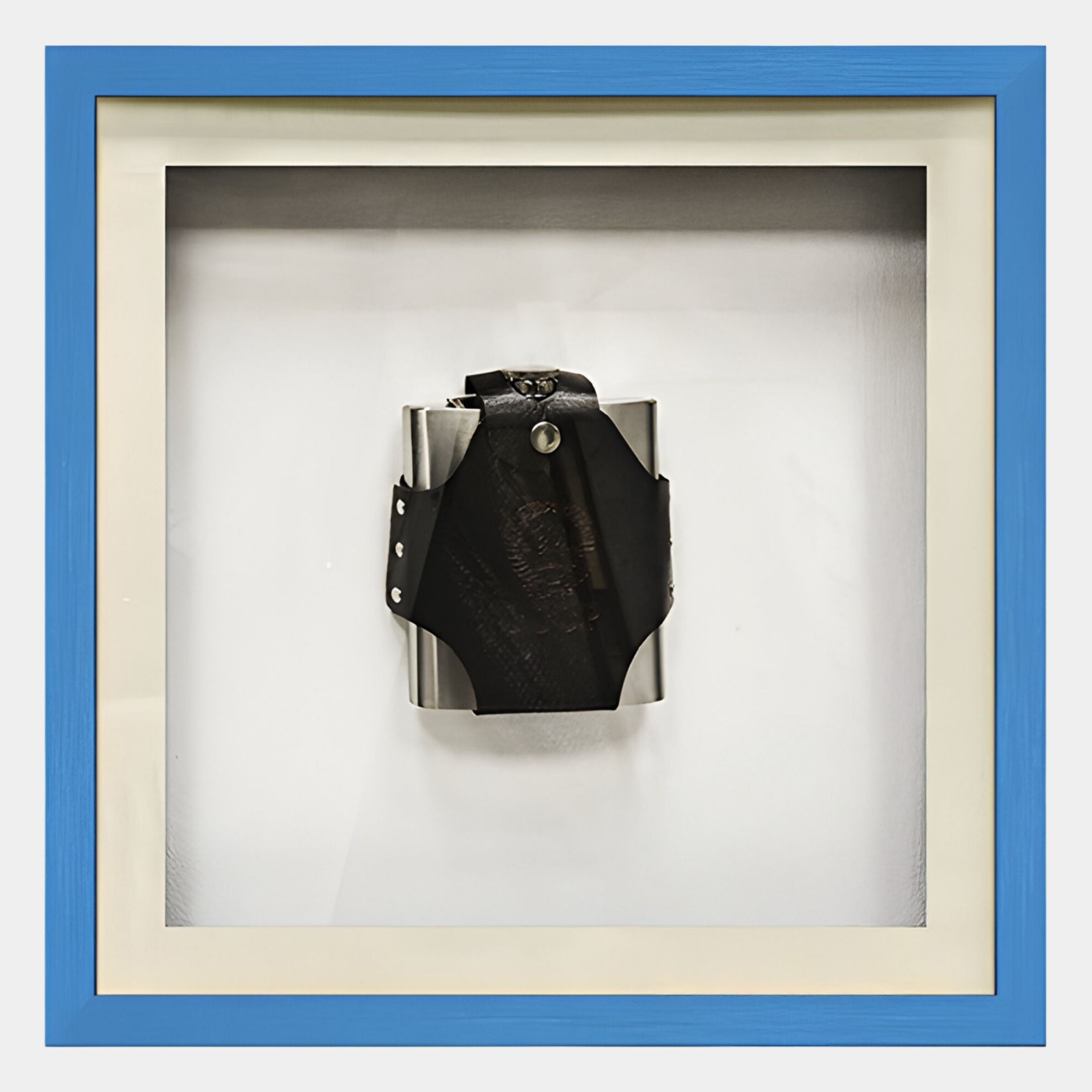 The Valet Noir Leather Flask Blue Framed Wall Art by Giant Sculptures features a stainless steel hip flask with black leather strap, showcased in a white shadow box frame with blue edges—a striking piece of modern décor.