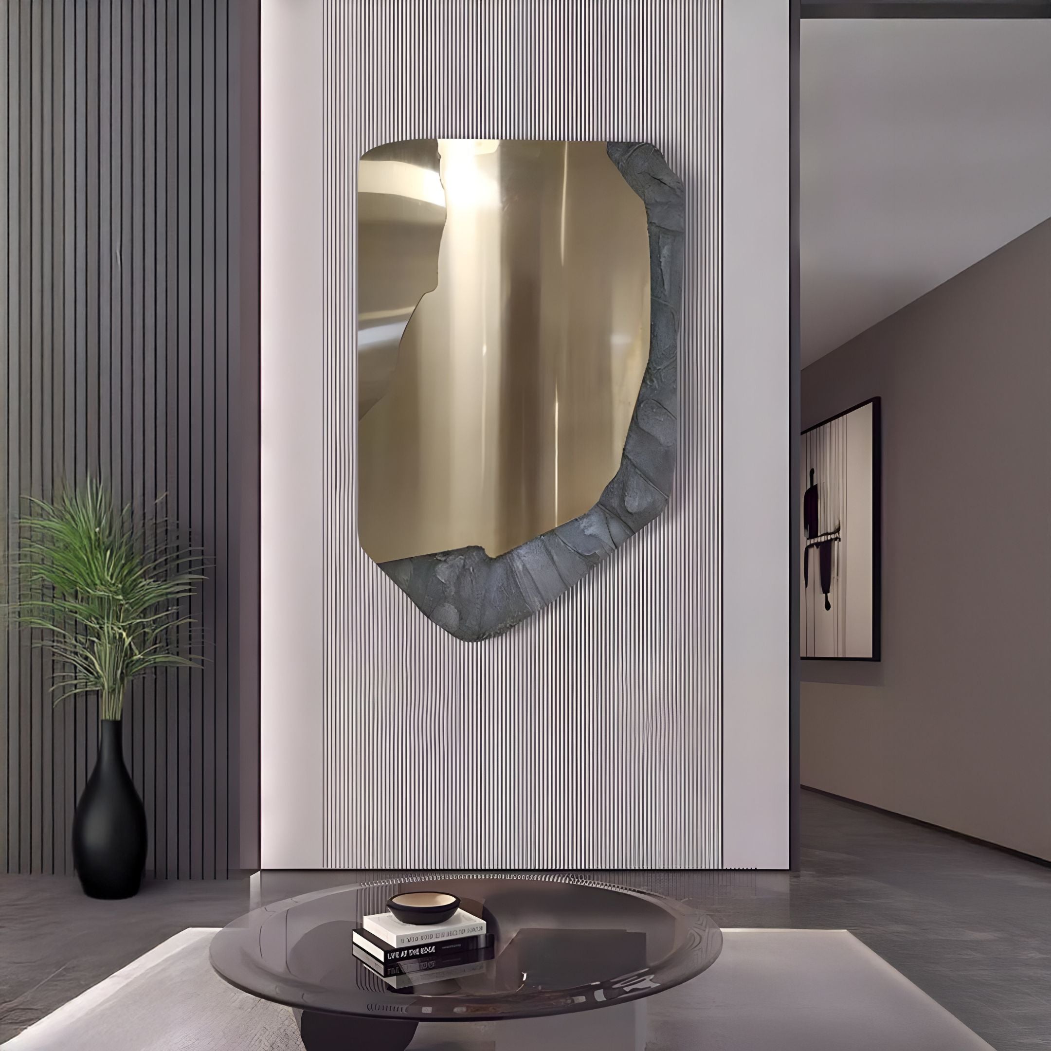 A modern living room showcases the Gildrift Gold Steel & Slate Grey Edge Textured 3D Wall Art by Giant Sculptures as a bold wall accent, along with a round glass coffee table, books, a black vase with a plant, and minimalistic neutral decor.