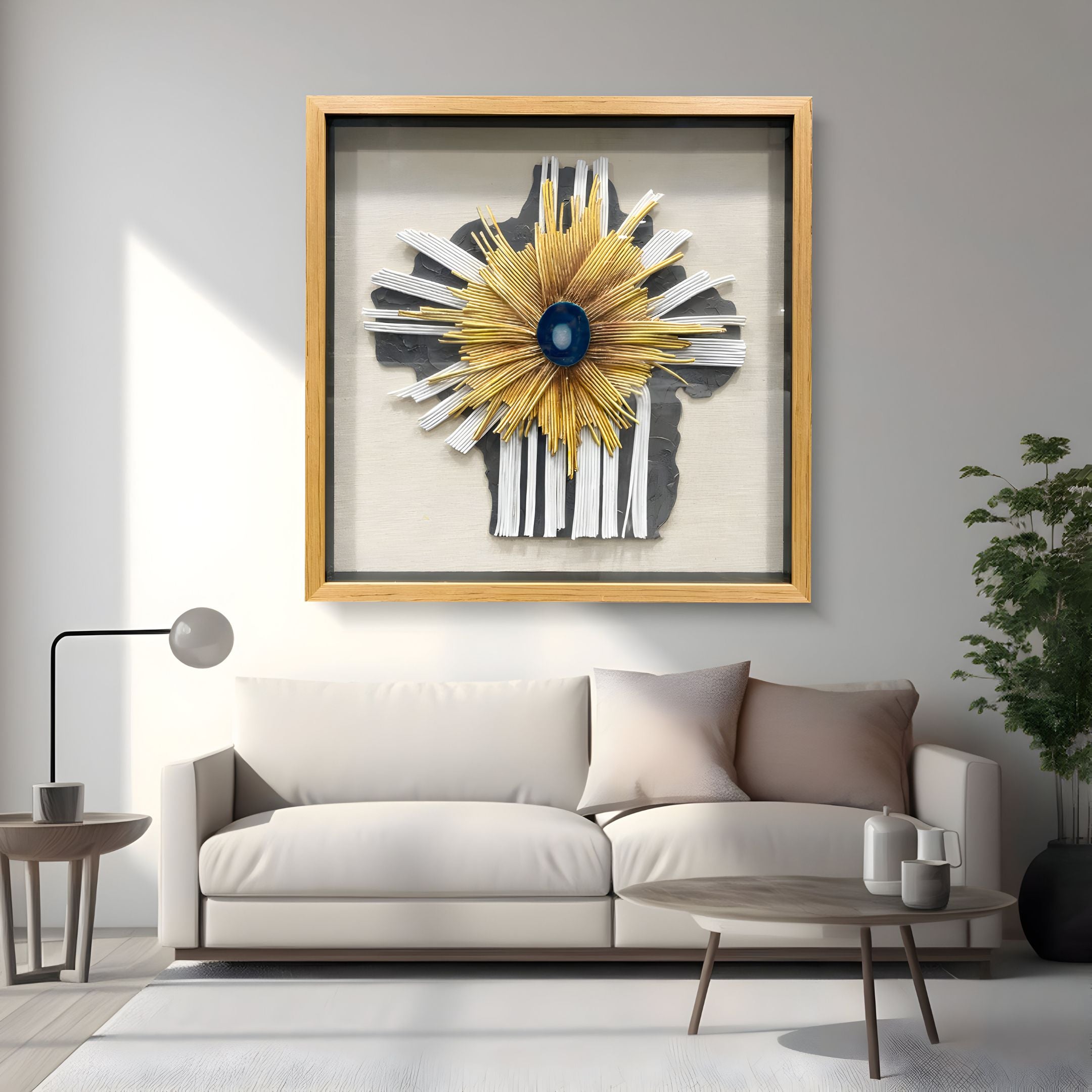 A modern living room features a light beige sofa, neutral pillows, and a round white coffee table. Above the sofa, Giant Sculptures' Asterfold I White & Yellow Sunburst 3D Wall Art adds a striking focal point with its abstract design in a wooden frame.