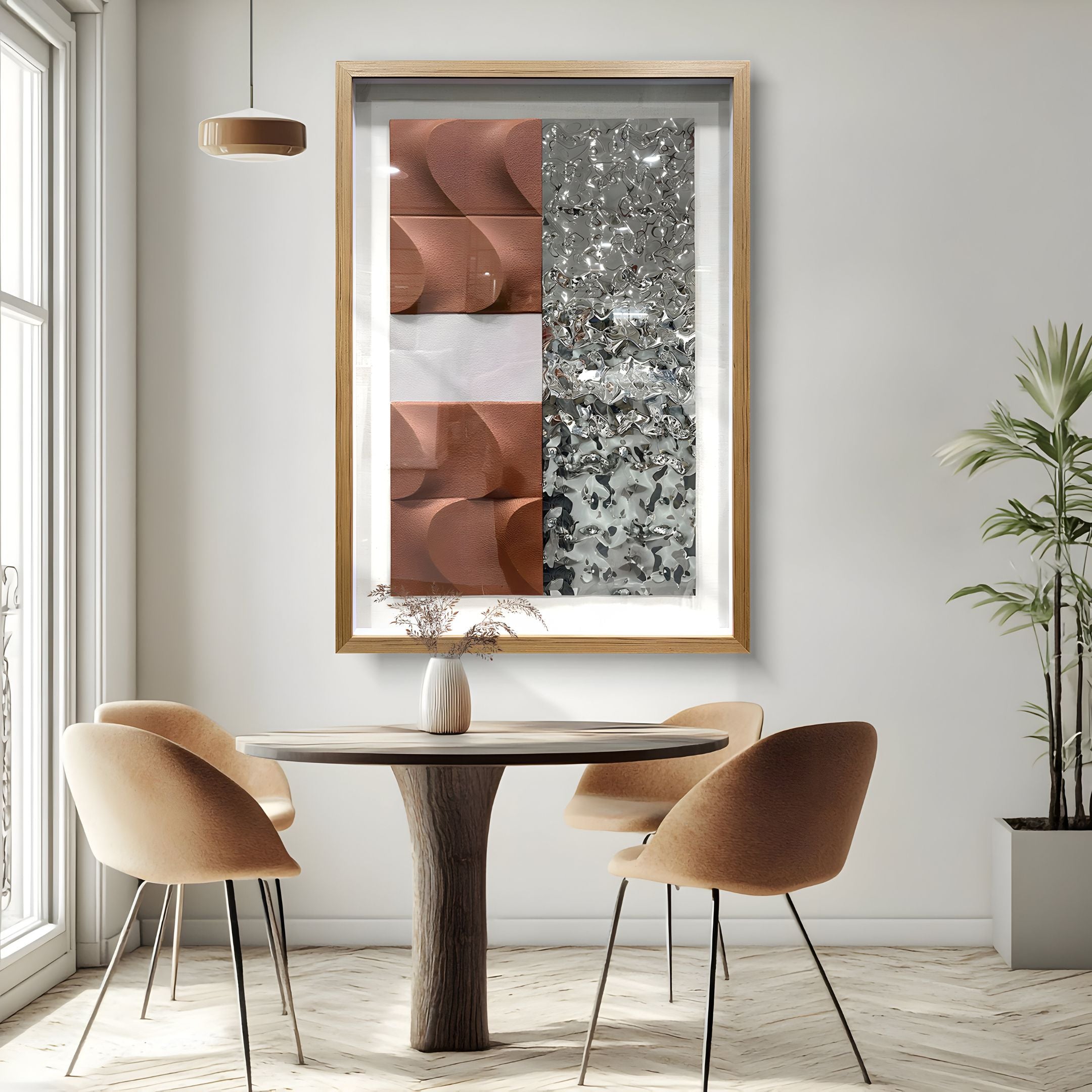 A modern dining area with a round wooden table, four beige chairs, and a vase of flowers is highlighted by the Giant Sculptures Crushline Terracotta & Silver Ripple Textured Metal 3D Wall Art above, plus a hanging light and potted plant near the sunny window.