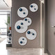 A modern hallway showcases the Orbiora Blue Orb 5-Panel Concentric Sphere 3D Wall Art by Giant Sculptures—white panels with black concentric circles and glossy blue orbs—creating a bold, contemporary accent near a window.