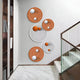A modern interior wall displays the Orbiora Orange & White Orb 5-Panel Concentric Sphere 3D Wall Art by Giant Sculptures, featuring five circular panels in orange and white beside a staircase with a glass railing and built-in bookshelf.