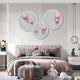 A modern bedroom in pink and gray features Giant Sculptures' Orbiora Pink Orb 3-Panel Concentric Sphere 3D Wall Art above the bed, complemented by decorative pillows, a plush toy, and stylish furniture.
