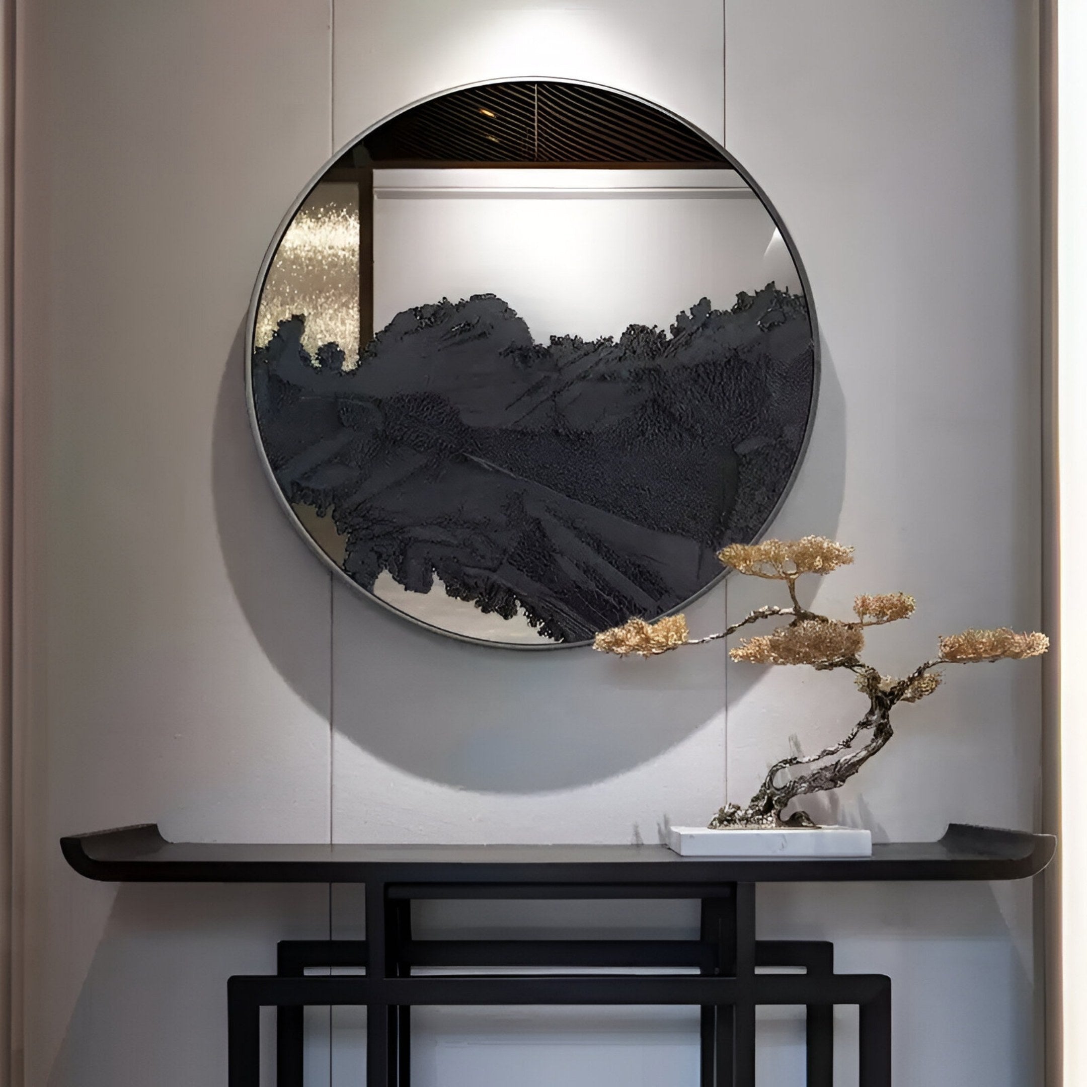 The Erosian Obsidian Drift Textured Round Mirror 3D Wall Art by Giant Sculptures hangs above a dark console table, with a small bonsai in a white pot for a minimalist, elegant arrangement.