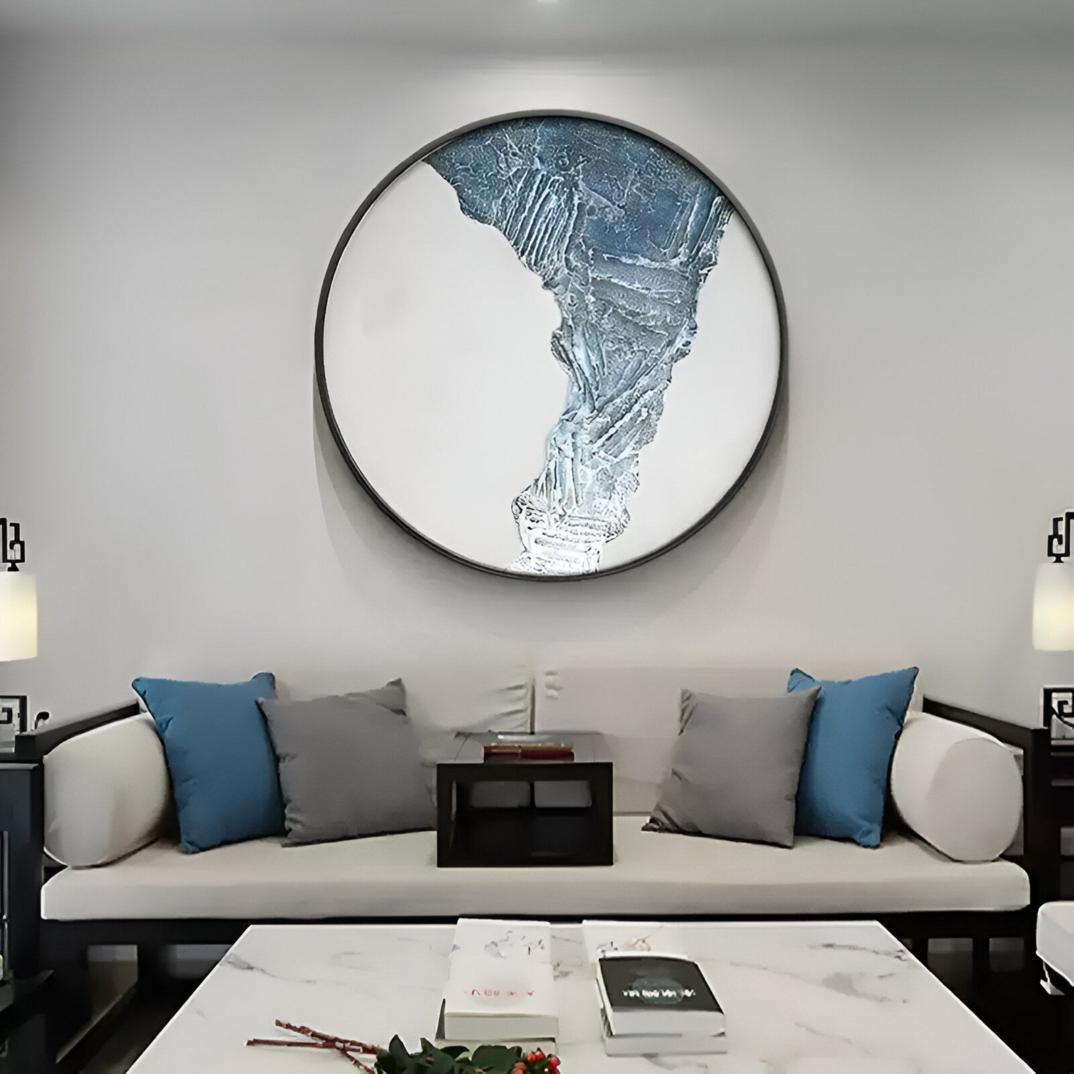 A modern living room features a light-colored sofa with blue and gray pillows, a marble coffee table, and the Cryora Blue Flow Textured Round 3D Wall Art by Giant Sculptures above the sofa for an artistic touch.