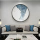 A modern living room features a light-colored sofa with blue and gray pillows, a marble coffee table, and the Cryora Blue Flow Textured Round 3D Wall Art by Giant Sculptures above the sofa for an artistic touch.