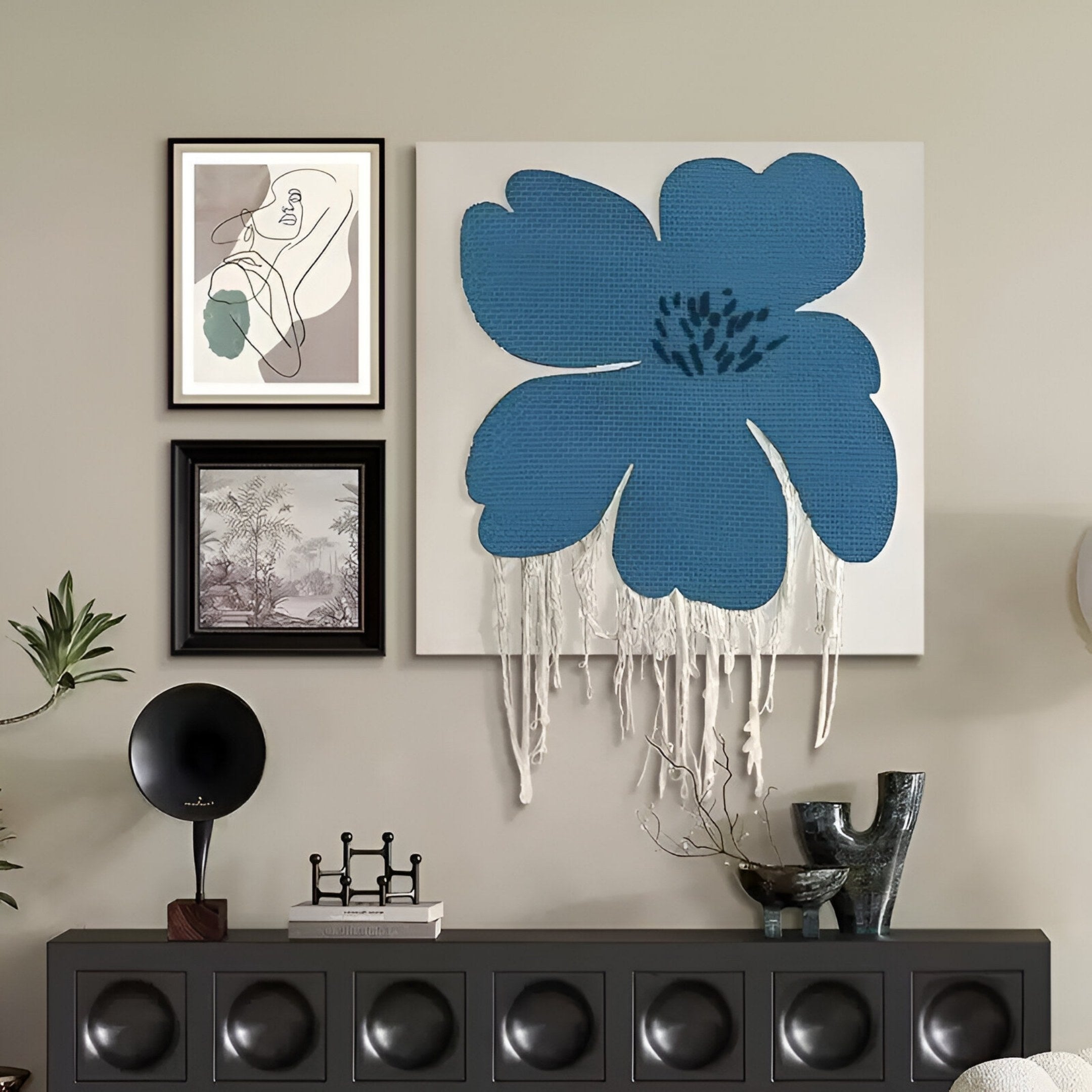 A modern living room wall showcases the Florayne 3-Set Blue Woven Textured 3D Wall Art by Giant Sculptures, paired with abstract and landscape prints. A black console with decor accents the scene.