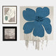 The Florayne 3-Set Blue Woven Textured 3D Wall Art by Giant Sculptures features a large blue abstract floral piece, a minimalist line portrait in neutral tones, and a black-and-white framed landscape with trees and wildlife.