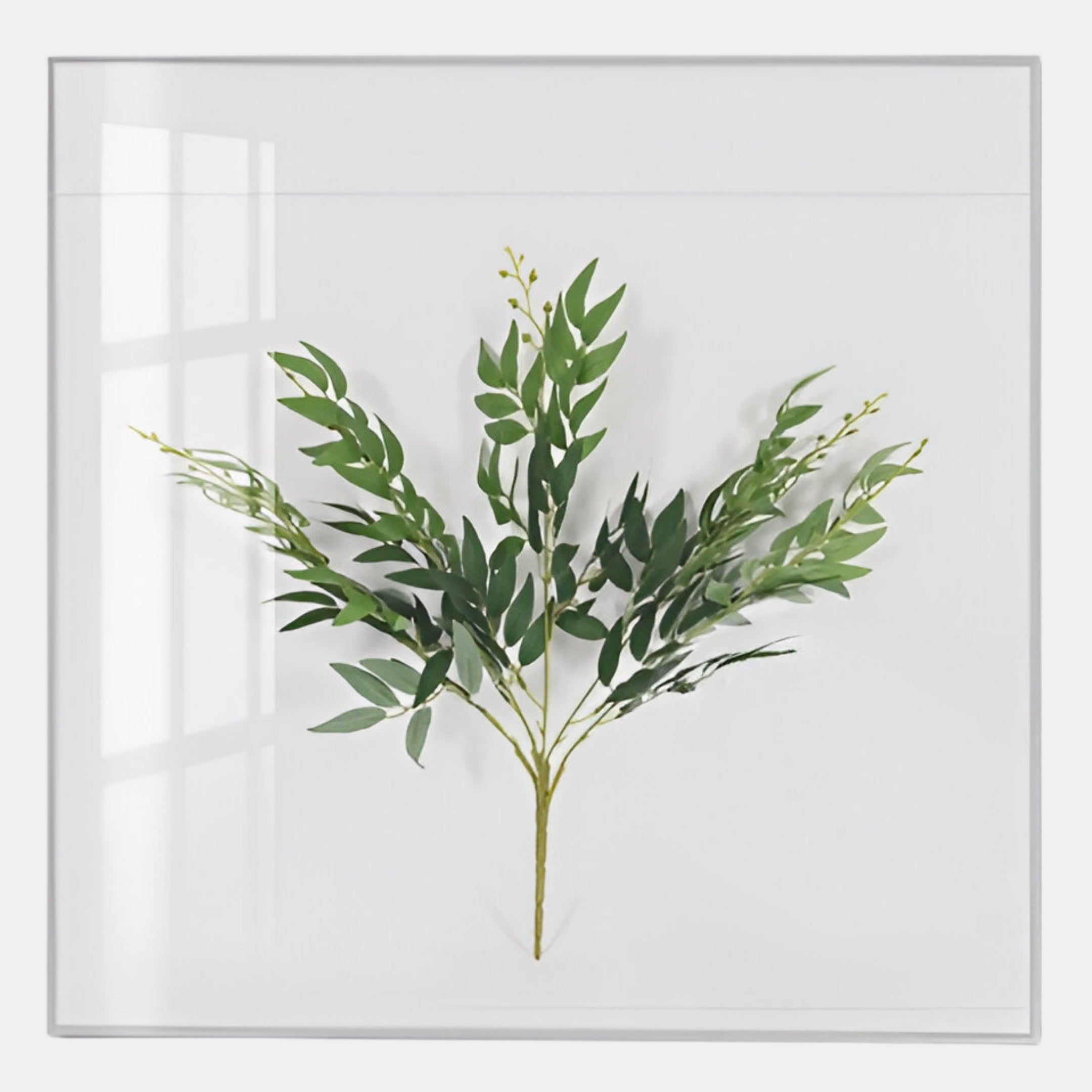 The Florvara Eucalyptus Stem Botanical Clear Acrylic 3D Wall Art by Giant Sculptures features a single green leafy branch on a white background with a square frame, casting a soft shadow—perfect modern décor for any space.