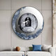 The Portara Silver Archway Illusion Round 3D Wall Art by Giant Sculptures, featuring a metallic, artistic border, hangs above a modern white sofa with blue and white cushions and a brown decor object in a contemporary living room.