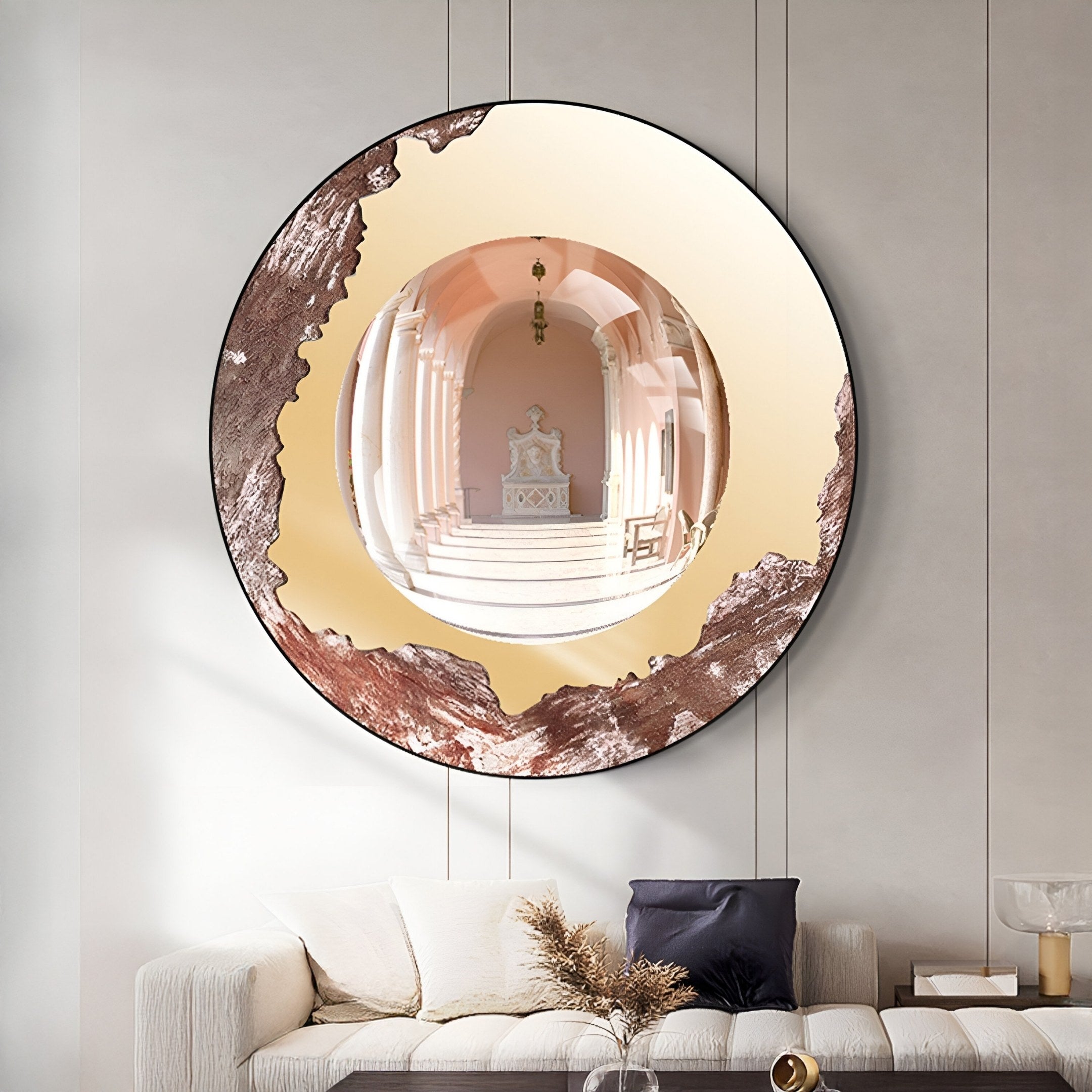 The Portara Rose Archway Illusion Round 3D Wall Art by Giant Sculptures, with its decorative uneven edge, hangs above a white sofa with black and white cushions, reflecting an ornate hallway with columns and an arched doorway.