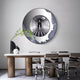 A modern dining room features the Portara Monochrome Hall Illusion Round 3D Wall Art by Giant Sculptures above the table, surrounded by zebra-patterned chairs. A black vase and a white object add to the minimalist, stylish atmosphere.