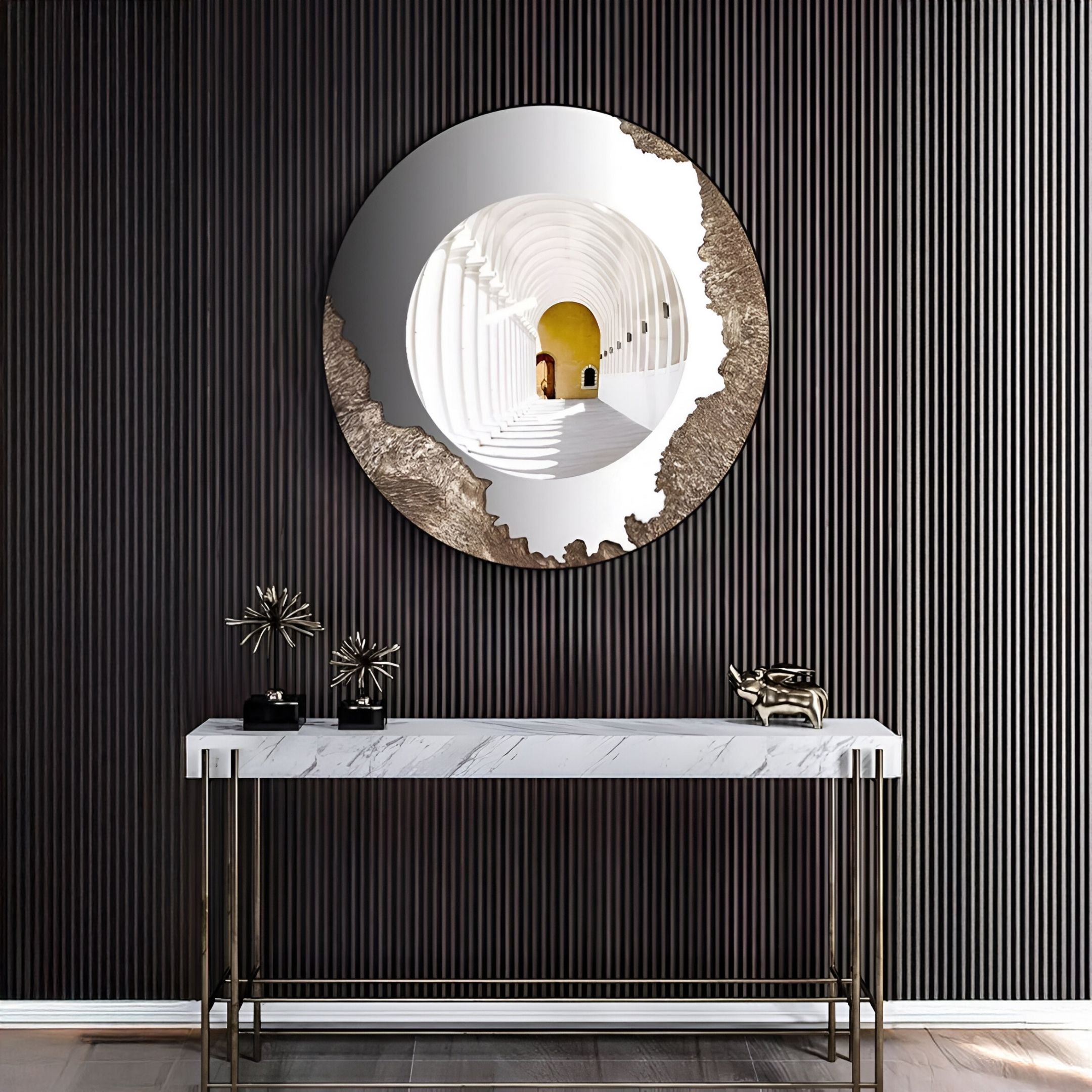 The Portara White Cloister Illusion Round 3D Wall Art by Giant Sculptures, featuring an abstract metallic edge, hangs above a white marble console on a dark striped wall. The mirror reflects an arched hallway; decor and a small box rest below.