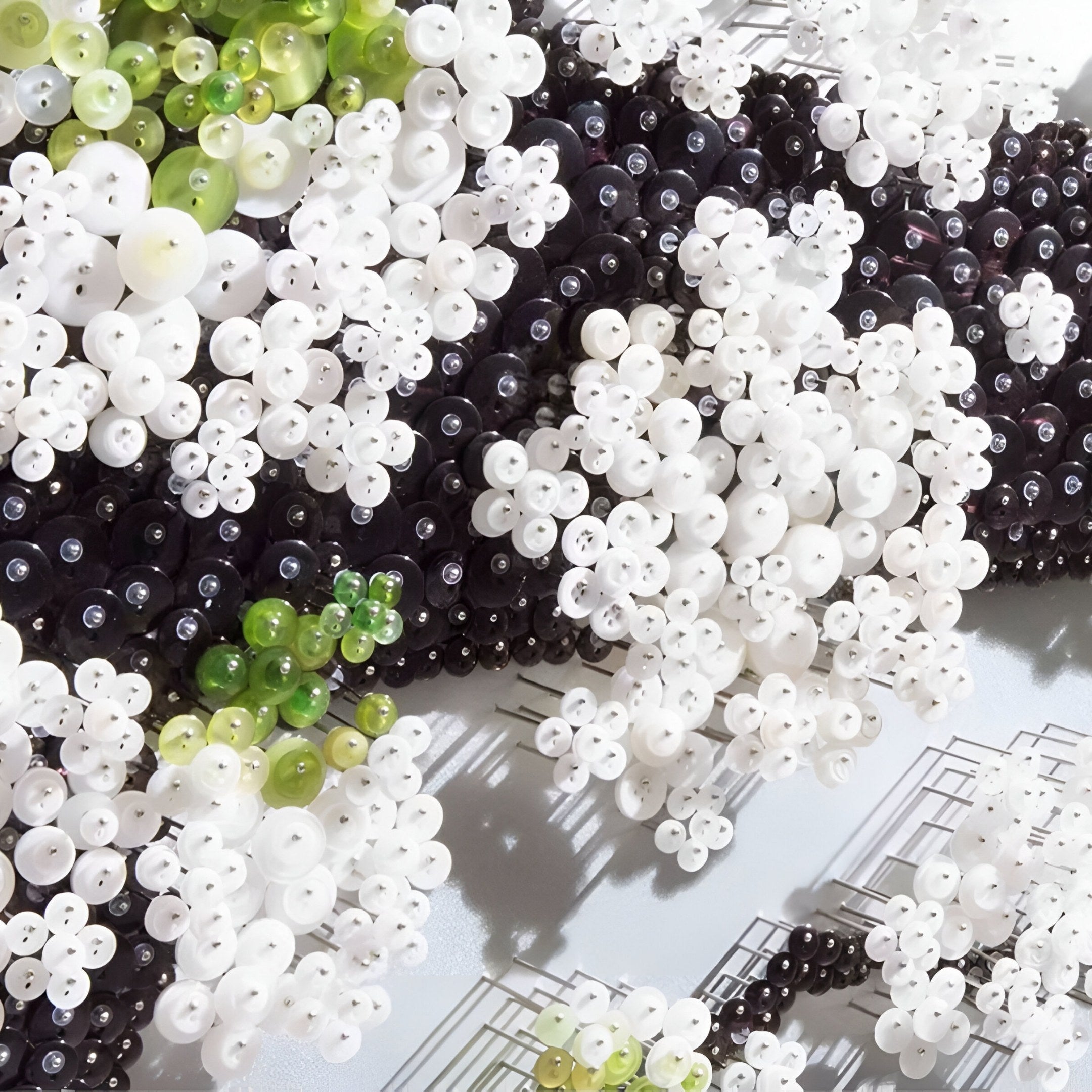 A close-up of the Florivine Aqua Blossom Tree Button 3D Wall Art by Giant Sculptures, featuring clusters of white, black, and green beads in floral patterns on a light background with metallic geometric accents.