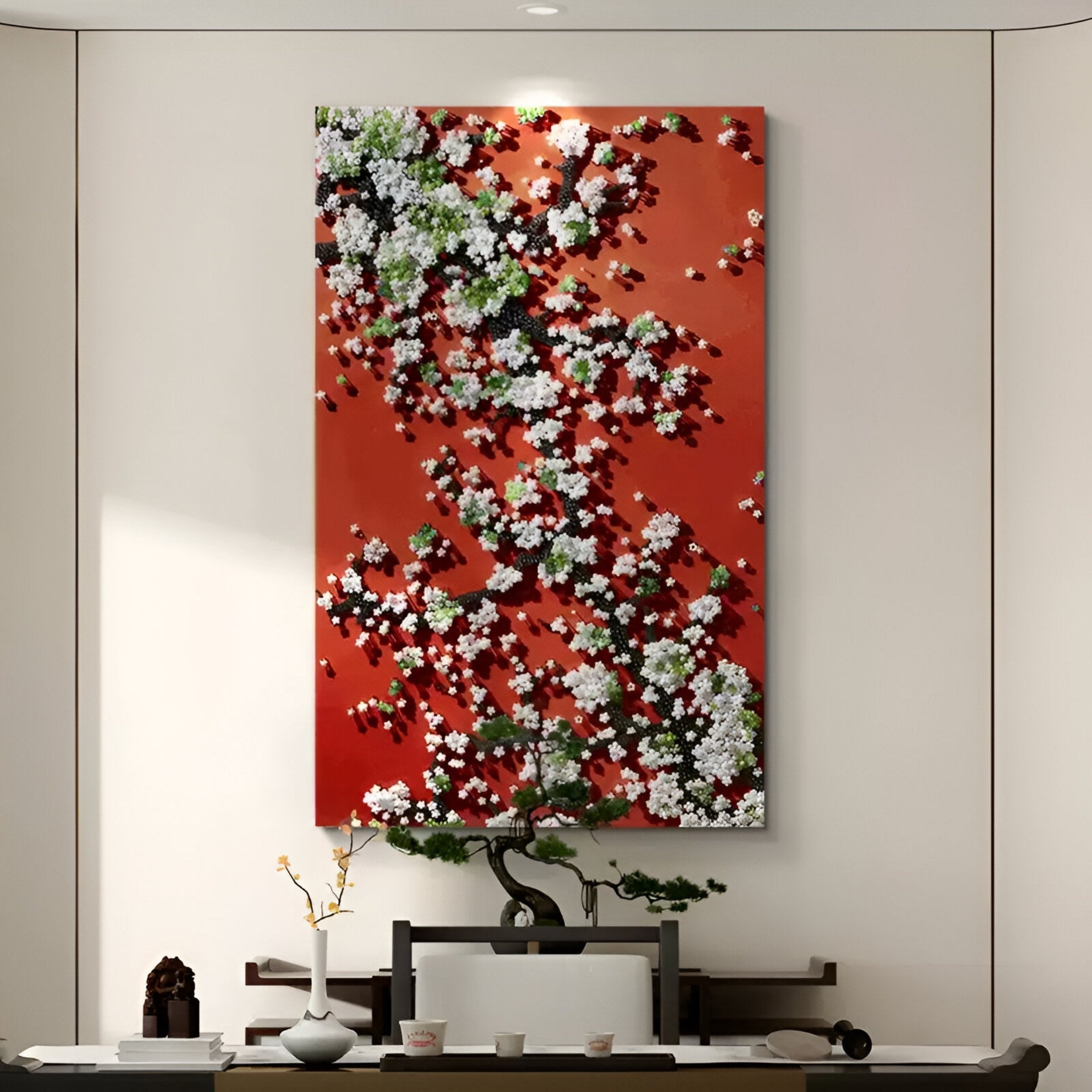 A modern minimalist room showcases Giant Sculptures’ Florivine Crimson Blossom Tree Button 3D Wall Art—an abstract crimson, white, green, and black piece—above a table with a bonsai tree, vase of branches, and tea set.