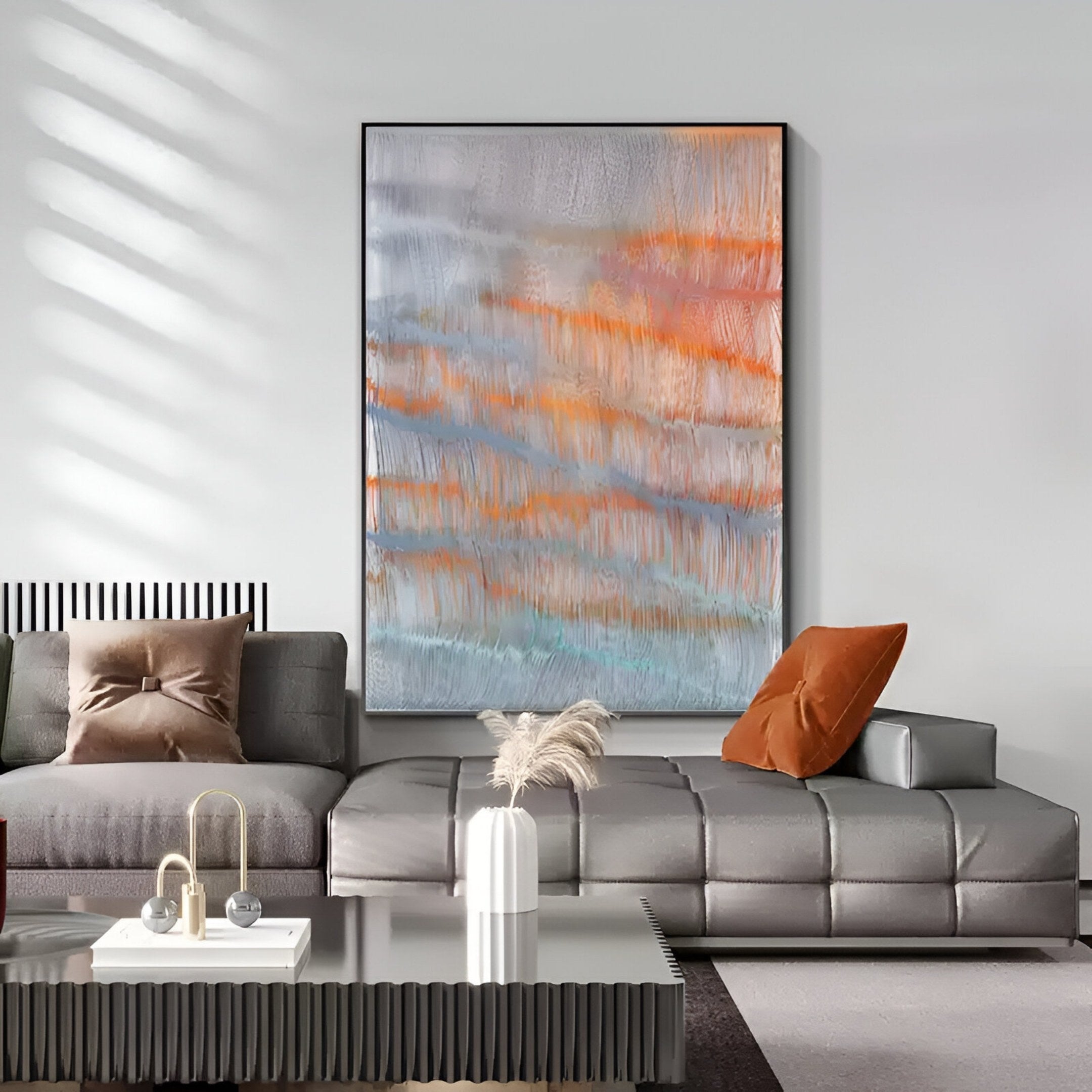 A modern living room showcases the Aqualis Sunset Orange & Blue Textured Abstract 3D Wall Art by Giant Sculptures above a gray sectional with brown cushions, a coffee table, and minimalist decor, sunlight streaming through blinds onto the wall.