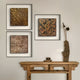 A wooden console table with a small bowl and tall sculpture stands against a beige wall, above which three Fiorenze Bronze Textured Square 3D Wall Art pieces by Giant Sculptures are neatly arranged.