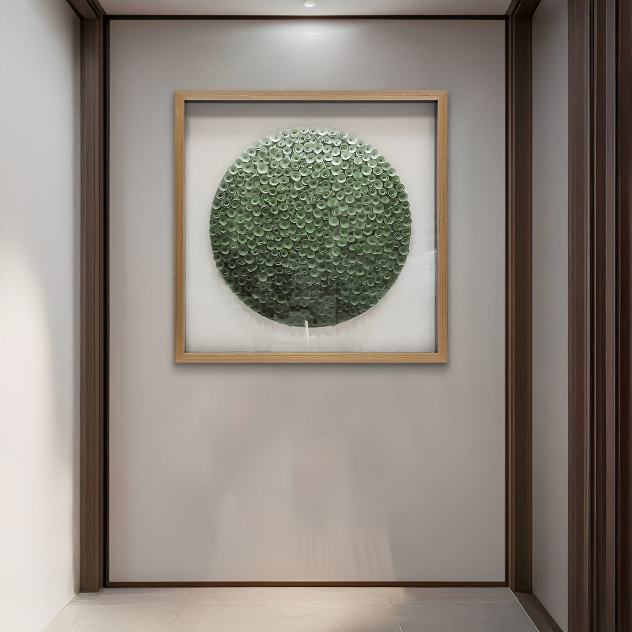 The Aureliare Forest Green Rolled Floral Framed 3D Wall Art by Giant Sculptures is displayed on a white wall in a minimalist hallway with recessed lighting and light tile floors, accentuating elegant forest green decor.