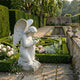 Praying Angel Marble Outdoor Sculpture kneeling on a stone base in a formal garden with box hedging, pink roses, a reflecting pool, and tall green hedges.