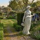 Giant Sculptures Hebe Cupbearer Angel Marble Outdoor Sculpture in white marble, 180cm, shown in a lush English garden with delphiniums, roses, and a stone archway.