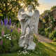 Large Winged Angel Marble Outdoor Sculpture by Giant Sculptures, 180cm white marble figure with flowing robes and dramatic feathered wings, displayed in a garden with purple delphiniums and pink foxgloves.