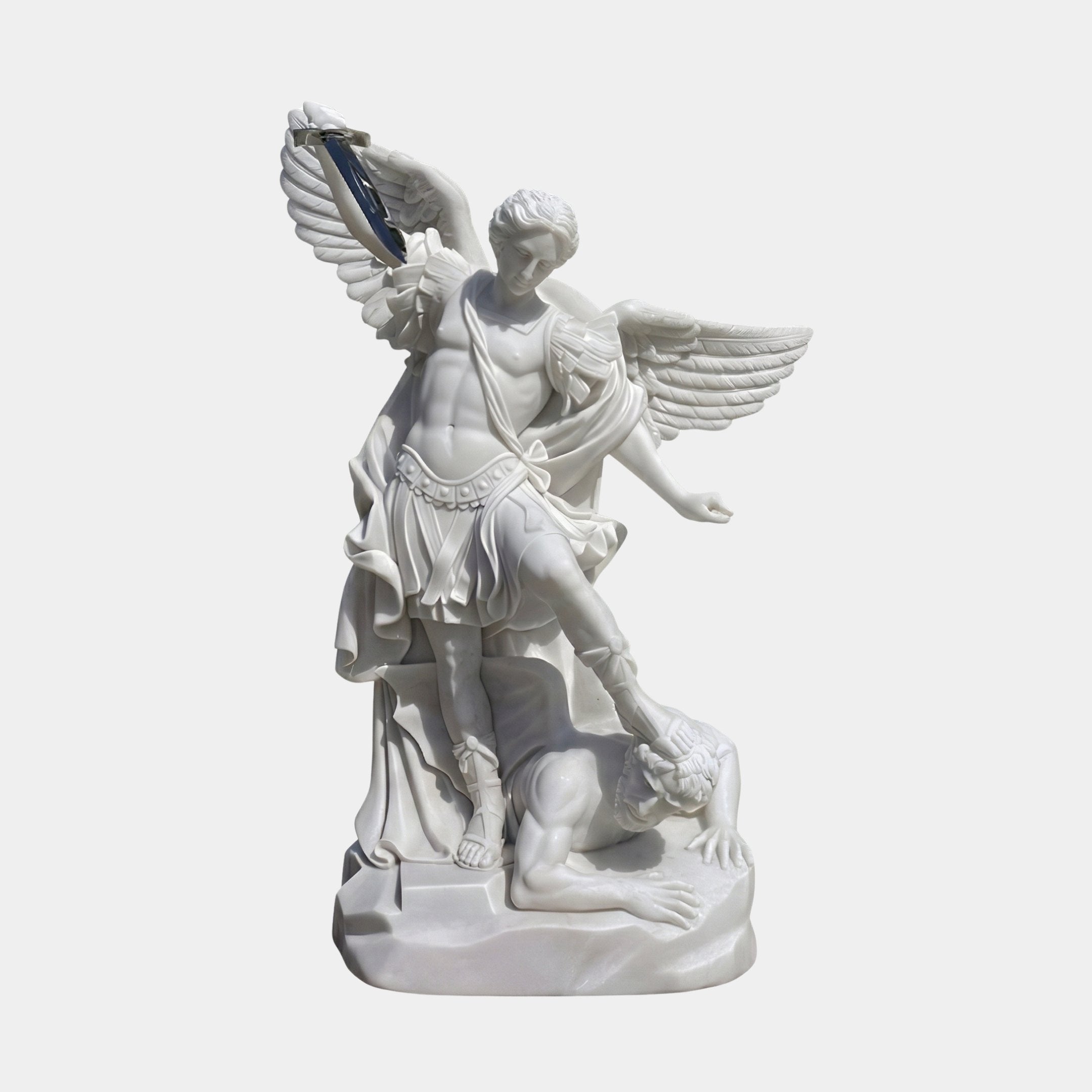 St Michael Angel Marble Outdoor Sculpture by Giant Sculptures, 180cm white marble archangel with spread wings and sword standing over a defeated figure, shown against a plain light background.