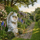 Winged Angel Marble Outdoor Sculpture by Giant Sculptures, 160cm tall, kneeling in flowing robes with detailed wings, set in an English garden border with roses and delphiniums.