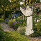 Female Angel Marble Outdoor Sculpture - 80cm by Giant Sculptures, a white marble winged angel cradling a child, displayed in a lush English garden with colorful flower borders.