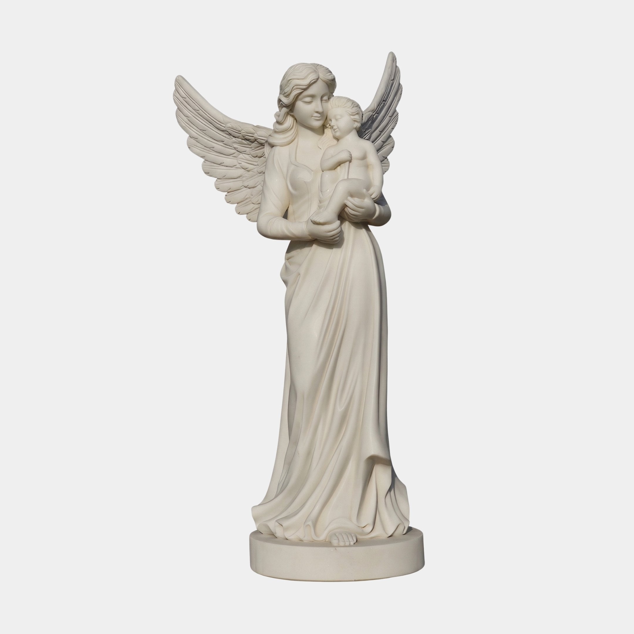 Female Angel Marble Outdoor Sculpture – 80cm by Giant Sculptures, depicting a serene winged angel cradling a child, carved in white marble with flowing robes and detailed wings on a round base, shown against a plain light background.