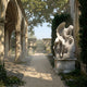 Weeping Angel Marble Outdoor Sculpture by Giant Sculptures, 130cm white marble figure with bowed head and draped wings in a grief pose, displayed beside gothic arches in a garden setting.