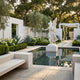 Flower Crown Angel Marble Outdoor Sculpture by Giant Sculptures, 200cm white marble winged figure in flowing robes beside a reflective pool in a formal garden setting with hedges and olive trees.
