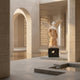 Gold Life-Size Angel Marble Outdoor Sculpture by Giant Sculptures, 225cm tall, depicting a winged angel in flowing robes with white and golden two-tone marble finish on a dark base, shown in a sunlit stone courtyard with arches and a reflecting pool.
