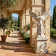 Life-Size Angel Marble Outdoor Sculpture by Giant Sculptures, 180cm white marble winged angel in flowing robes on a square pedestal, displayed beside a stone archway colonnade with lavender and olive trees.