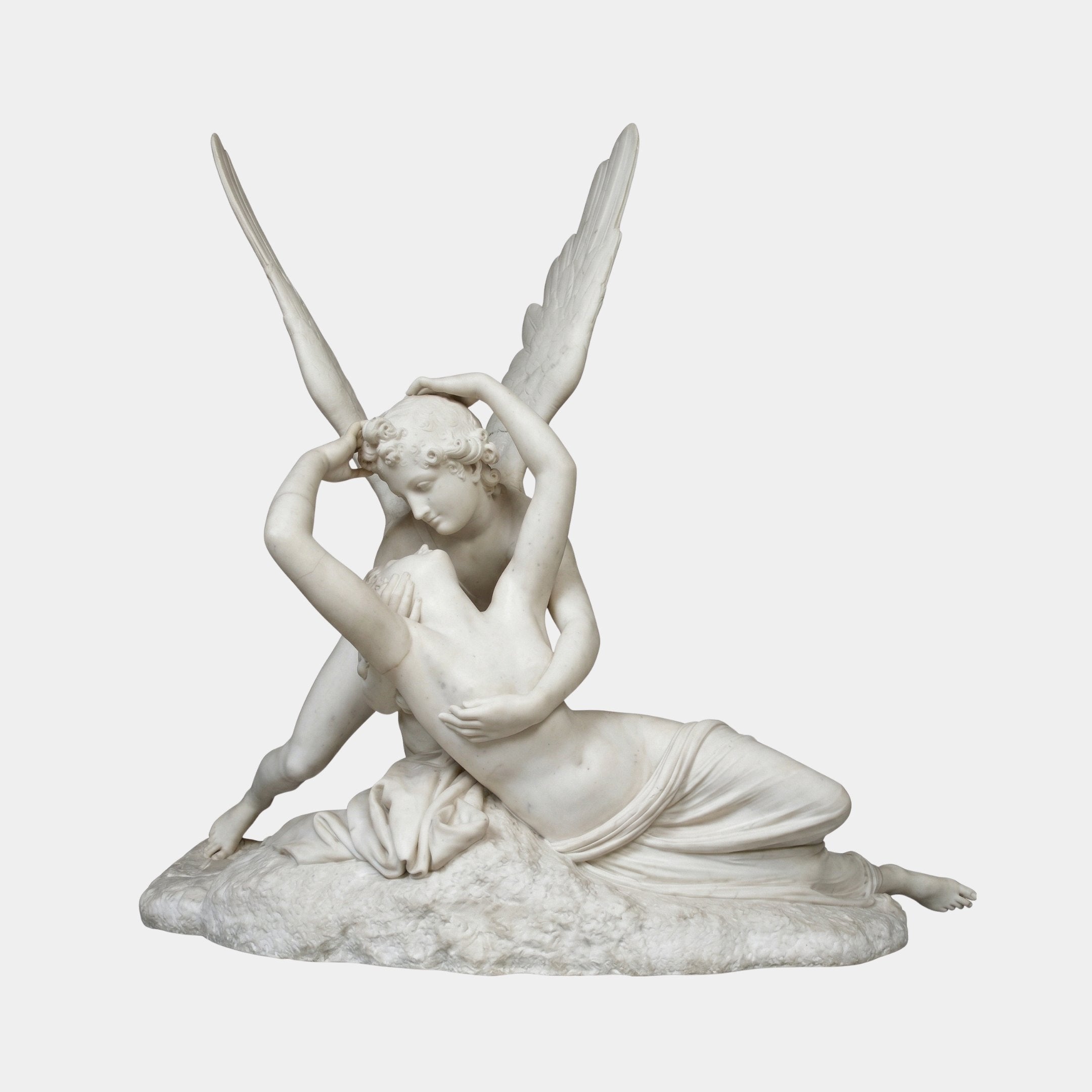 Eros and Psyche Angel Marble Outdoor Sculpture by Giant Sculptures, depicting the winged Eros embracing a reclining Psyche on a natural marble base, white marble finish, plain light background.